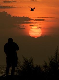 Randal Ruvalcaba of Brookfield, Wis., takes pictures of the sun rising over Lake Michigan Aug. 28, 2007 in Milwaukee. Ruvalcaba was out early to take pictures of the lunar eclipse.